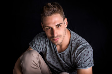 Fototapeta premium Attractive man with shirt, on dark background in studio, shot from above, looking at camera