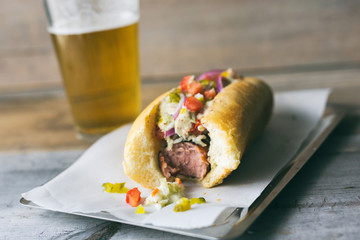 Hot dog, half eaten with a glass of beer. 