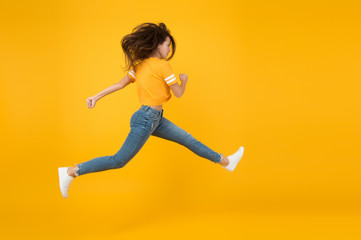 Fototapeta na wymiar Energetic woman running or jumping. Skinny jeans suits her. Sexy girl yellow background. Sensual girl in casual style. Feel inner energy. Pretty girl with long hair. Fashion style. Beauty and make up