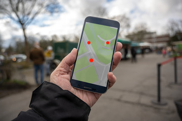 Hand is holding a smartphone with a coronavirus tracking app in the city, help to protect against...
