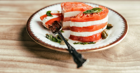 Layered caprese salad with heirloom tomatoes and buffalo mozzarella. Garnished with basil olive...