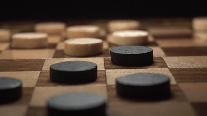 Obraz na płótnie Canvas Game of checkers. Close up footage of player make his turn with black chip on black background.