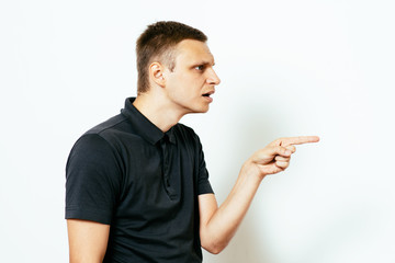 Closeup side view portrait of young man, pointing with finger at someone or something. Positive human face expressions, emotions, feelings, attitude, approach
