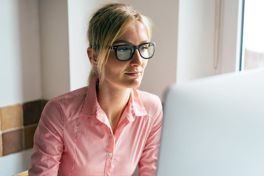 Business Pretty Woman In Glasses Looks At The Computer Monitor. Home Office. Online Working. Remote Occupation. Work From Home. Quarantine And Isolation.