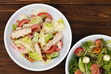white deep plates with fresh salad ingredients mixed with sauce placed on an attractive background. A place for a menu, banner or advertisement