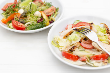 white deep plates with fresh salad ingredients mixed with sauce placed on an attractive background. A place for a menu, banner or advertisement