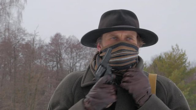 dangerous man with a gun puts on scarf on his face 