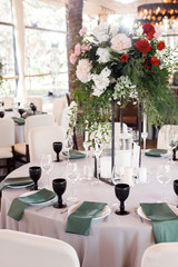 Festive wedding table setting with flowers, napkins, cutlery, glasses and candles, bright summer table decor. Wedding decor