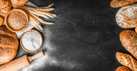 Bread with wheat and bowl of flour on dark board, White bakery food concept panorama or wide banner photo.