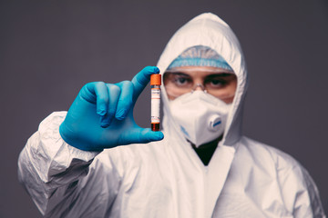 Fototapeta na wymiar Coronavirus pandemia. Healthcare to aid recovery from COVID-19. Man wear surgical gloves and mask, biohazard protection clothing with a coronavirus infected blood sample test.