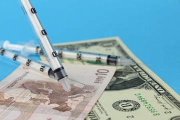 Syringe needles in a map of Europe on paper money. The spread of the virus, disease, epidemic. Search for a vaccine and treatment.