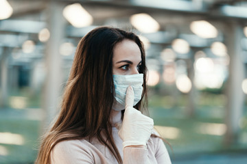 A young girl in a protective face mask points her finger at the mask