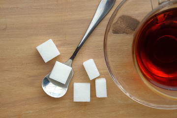 top view of sugar cube on spoon on wooden background 