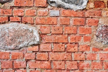 Ancient red bricks wall with old natural stones. Textured brickwork. Old rustic wall with bricks,cement and big natural stone. 