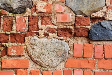 Ancient red bricks wall with old natural stones. Textured brickwork. Old rustic wall with bricks,cement and big natural stone. 