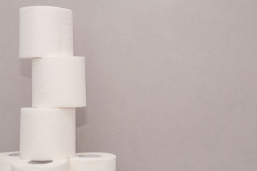 Tower made of white toilet paper rolls against the gray wall in bathroom