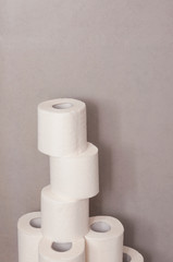 Tower made of white toilet paper rolls against the gray wall in bathroom