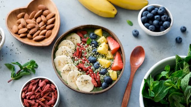 Smoothie bowl with various superfood toppings as banana chia seeds goji berries hemp seeds mango and blueberries. Green smoothie. Clean eating concept