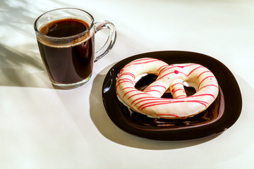 The pretzel cake is on a plate on the table. There is a Cup of coffee next to it. The photo of the Breakfast was taken in the morning light.