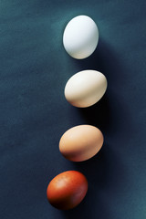 Four ordinary chicken eggs gradient from light to dark eggs on a dark background. Themed Easter image no to racism.