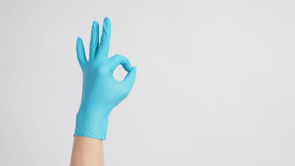 A Okay hand sign with gloves in left hand on white background.