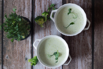 a plate of fresh broccoli cream soup with micro greens peas. on a dark wooden background