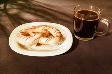 The pretzel cake is on a plate on the table. There is a Cup of coffee next to it. The photo of the Breakfast was taken in the morning light.