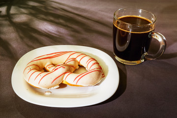The pretzel cake is on a plate on the table. There is a Cup of coffee next to it. The photo of the Breakfast was taken in the morning light.
