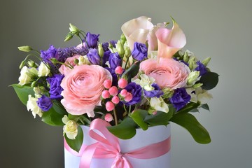 Spring bouquet in the box with pink ribbon. Floral composition with ranunculus, roses and alstroemerias flowers on neutral background
