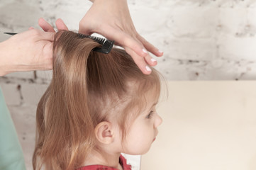 Naklejka premium hands of mother combing a little smiling girl
