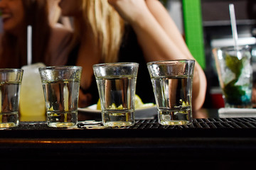 Shots de tequila en una barra con chicas de fondo / Tequila shots in a bar with girls in the background