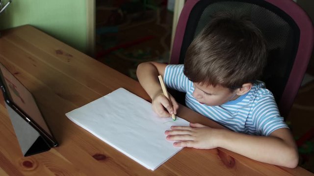 Cute boy writing letter A using tablet, home education while quarantine