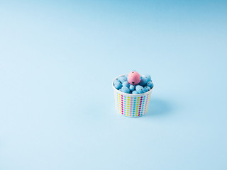 Easter pastel color eggs on blue backdrop with different pink one in paper bowl. Stand out from the...