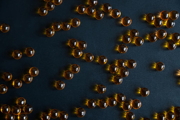 Round pills of fish oil, on a dark background