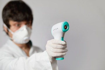 Doctor wearing a respirator N95 mask to use infrared forehead thermometer  to check body...