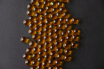Round pills of fish oil, on a dark background
