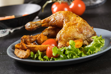 Roasted chicken legs with potato wedges and tomatoes