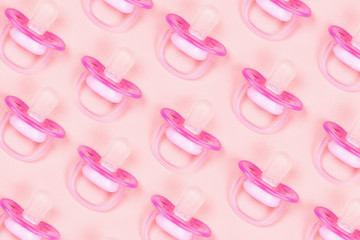 Pattern pink baby pacifiers, dummy with rubber nipple on pink background. Flat lay. Top view.