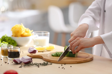 Female chef cooking food at kitchen table, closeup