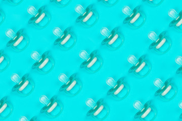 Pattern blue baby pacifiers, dummy with rubber nipple on blue background. Flat lay. Top view.