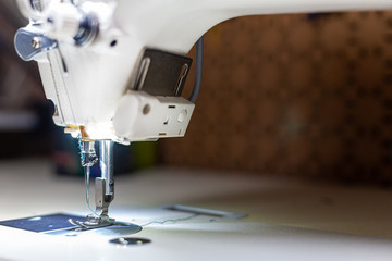 sewing machine sews a thin transparent white veil . sewing machine foot close up. sewing process.