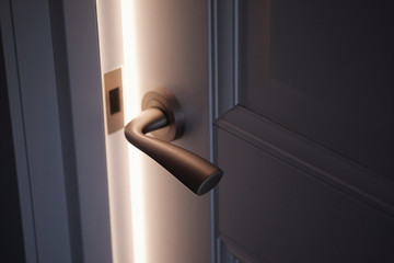 Bright light from open door and stainless steel doorknob or handle in classic art modern style in...