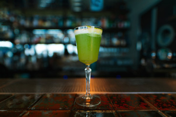 Green alcoholic cocktail on the bar counter. Close-up.