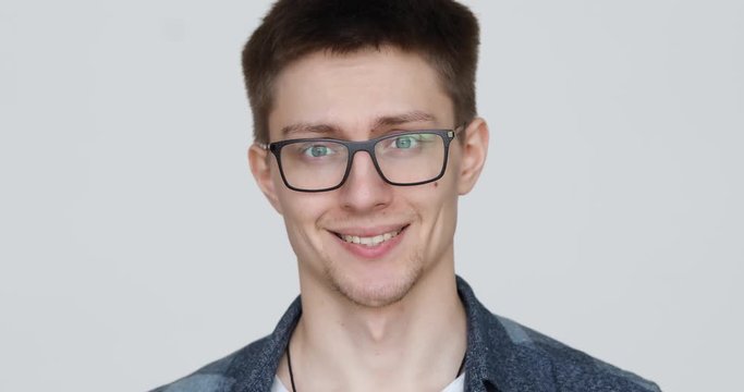 portrait of a guy with glasses who grimaces at the camera on a white background