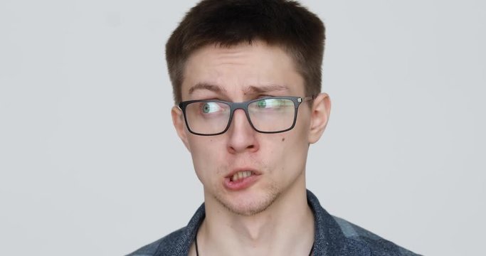 portrait of a guy with glasses who grimaces at the camera on a white background