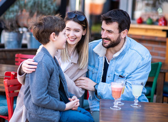 Family in a cafe/restaurant, smiling and talking.