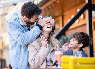 Family outside together in a cafe/restaurant laughing and enjoying their time.