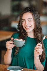 Beautiful woman having breakfast at outdoor cafe. Happy young urban woman drinking coffee
