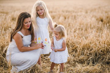 mom with two little girls in a wheat field. little princesses