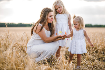mom with two little girls in a wheat field. little princesses